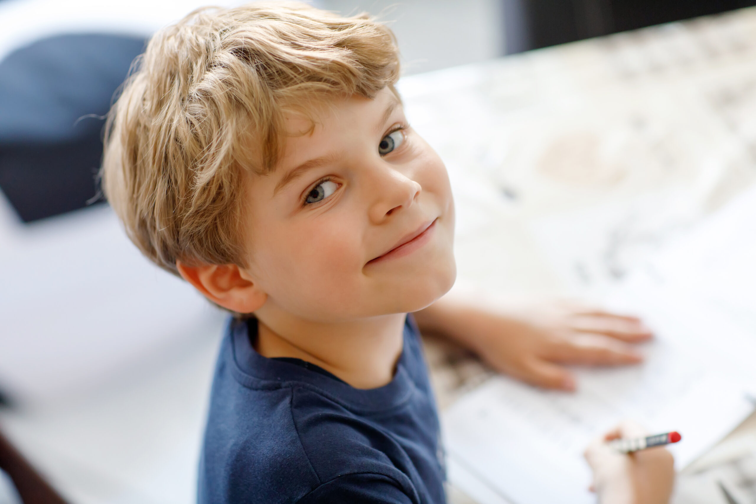 Happy smiling little kid boy at home making homework at the morning before the school starts. Little child doing excercise, indoors. Elementary school and education: Boy writing letters and numbers