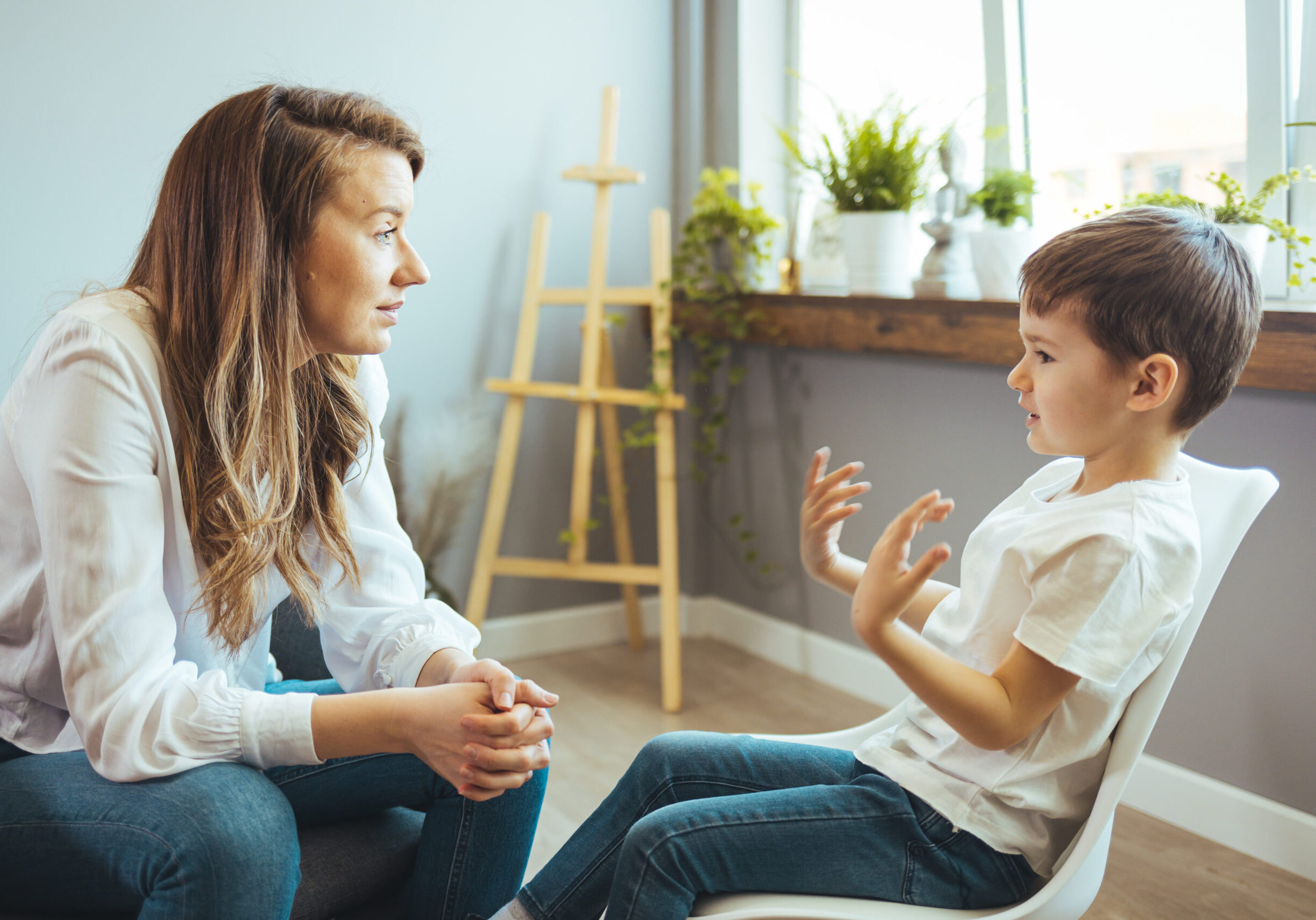 Young female psychologist working with little boy in office. Shot of a young child psychologist talking with a boy. Young female school psychologist having serious conversation with smart little boy